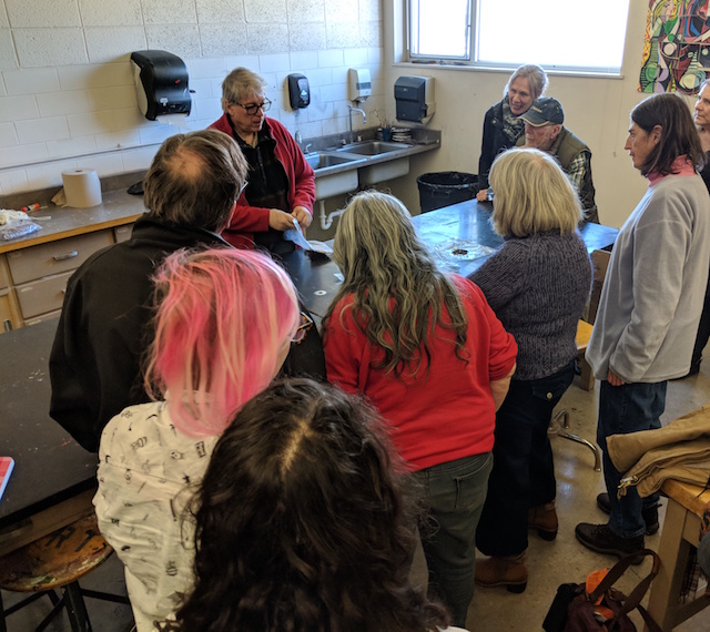 a man demonstrates a dyeing process to a group of people