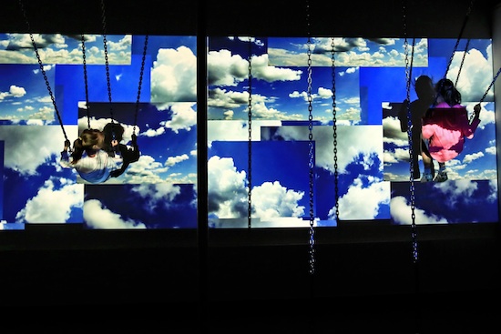 young chldren on swings against a video background of clouds and sky