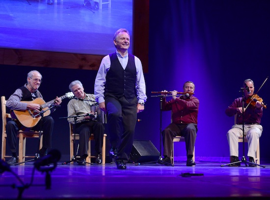 Irish step dancer Kevin doyle dancing onstage in front of a quartet of musicians