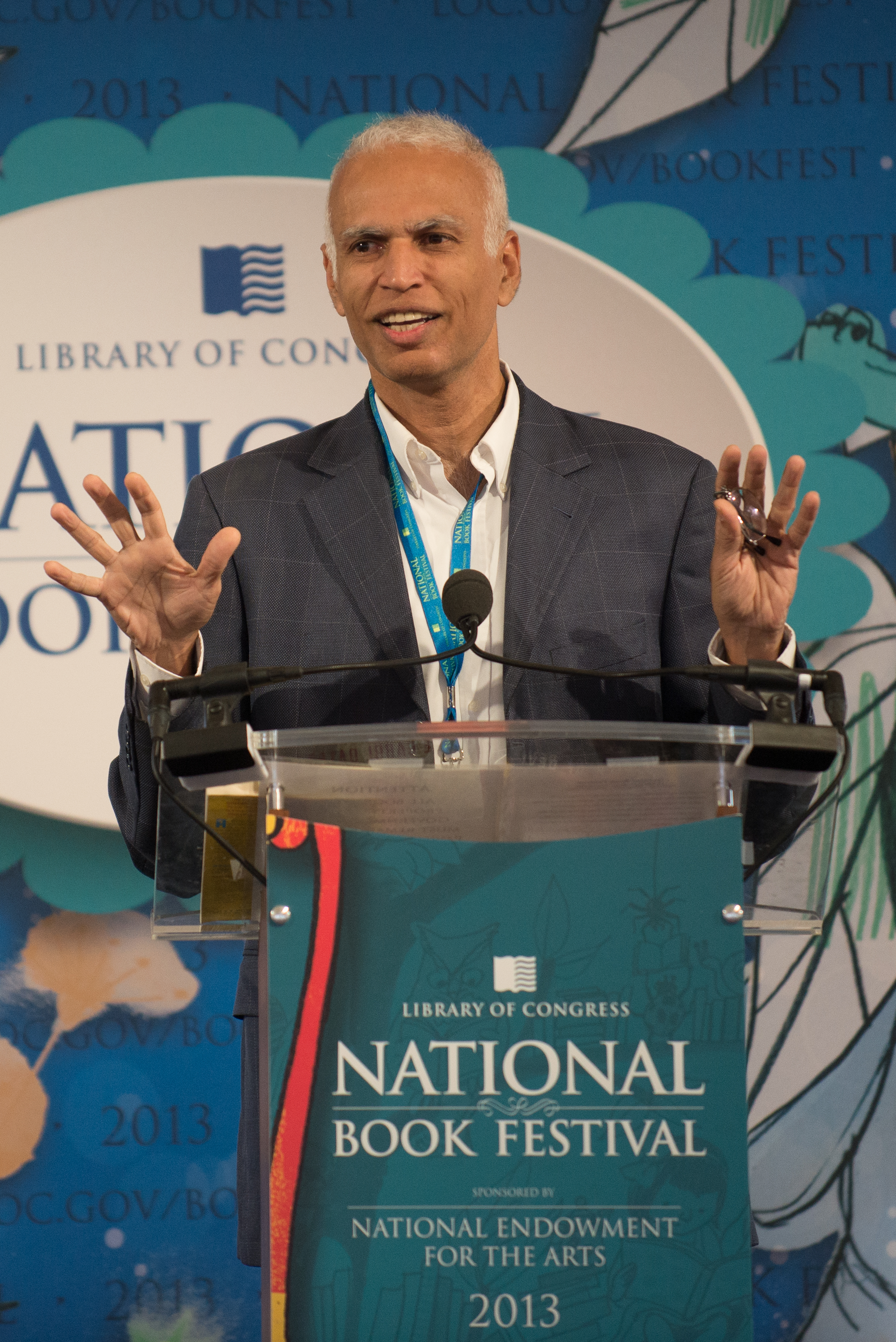 Manil Suri on stage behind a podium.