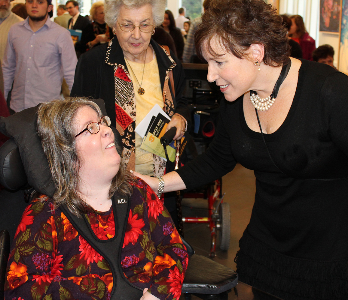 Woman talking with women in wheelchair.