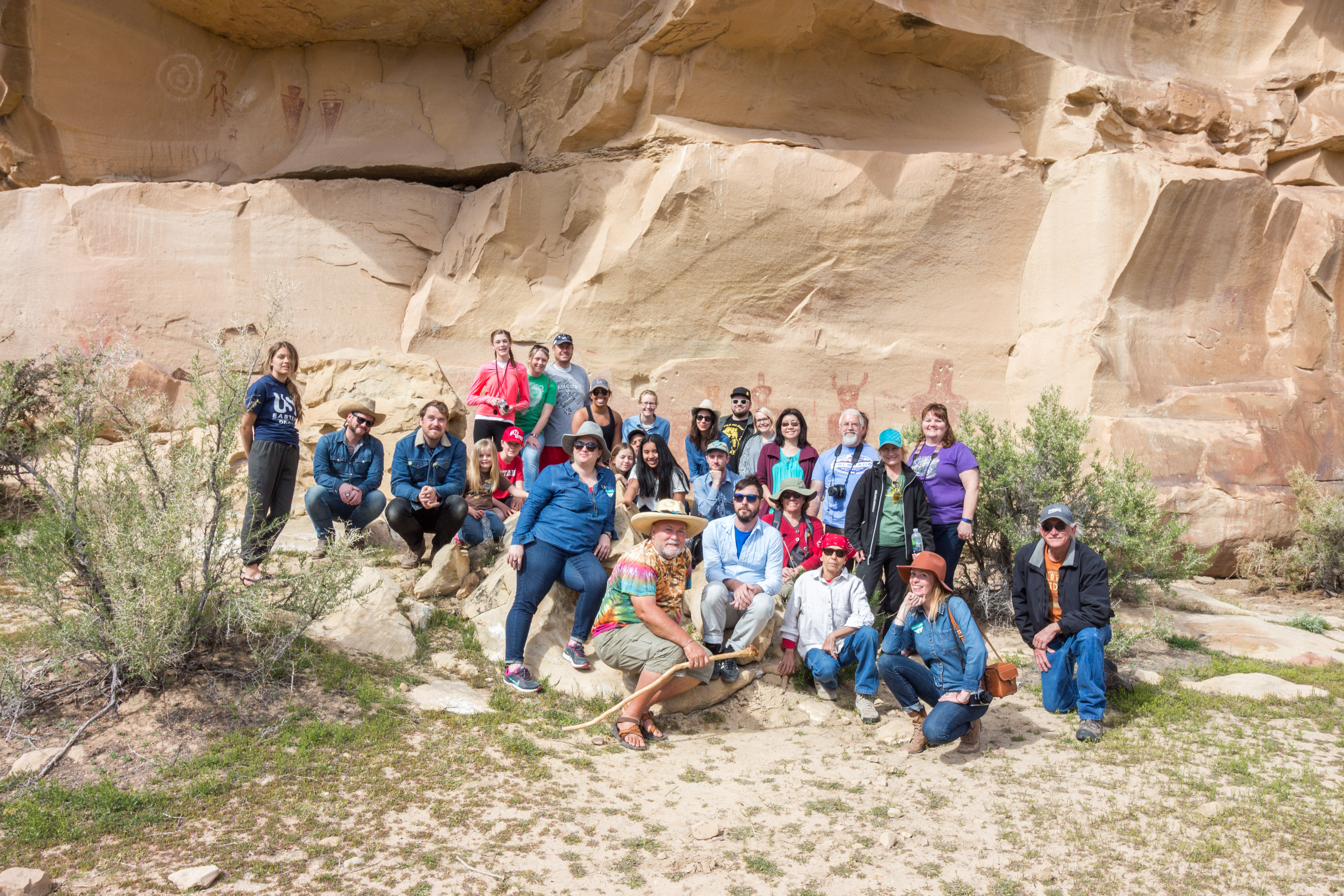 Group of people posing in front of a rock formation. 