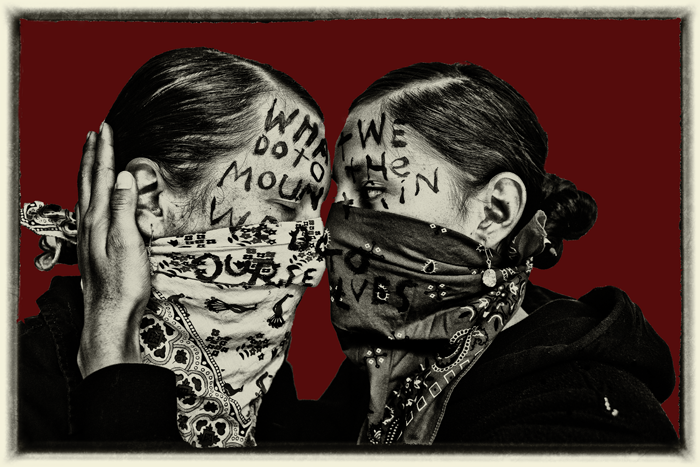 Mural of two Native women with handerchiefs over their faces holding each other.