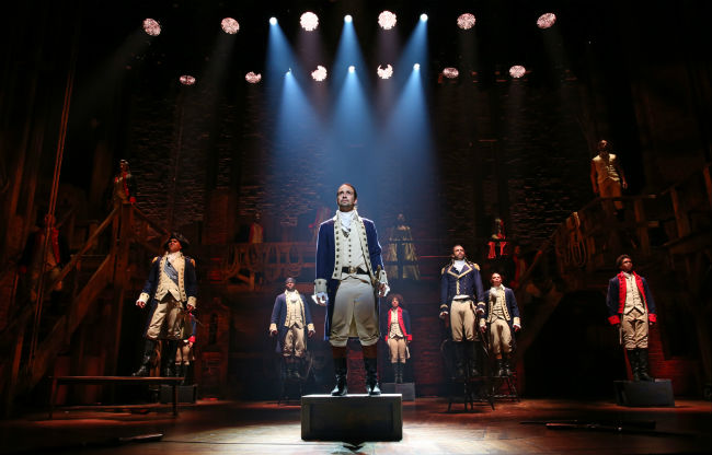 People standing on stage dressed as founding fathers