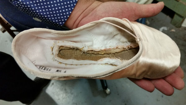 A pink satin pointe shoe without its liner