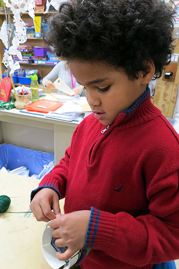 Young child in red sweater working on art project. 