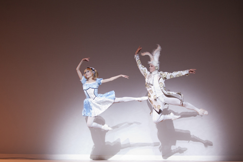 Woman dressed as Alice and man dressed as the White Rabbit jumping in the air. 