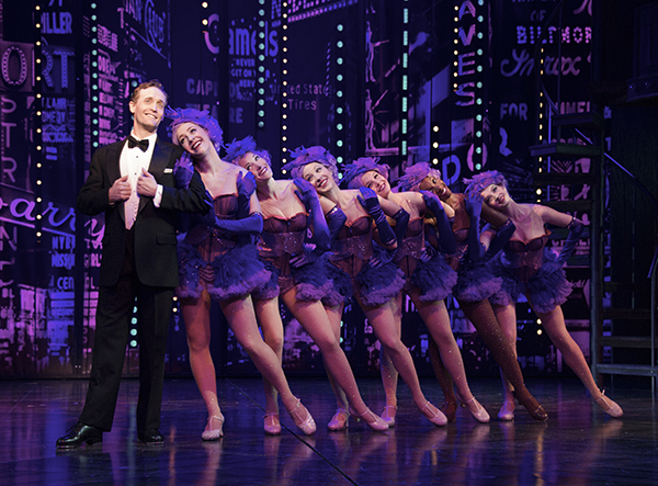 Actresses dressed as Fantasy Follies next to actor in tuxedo 