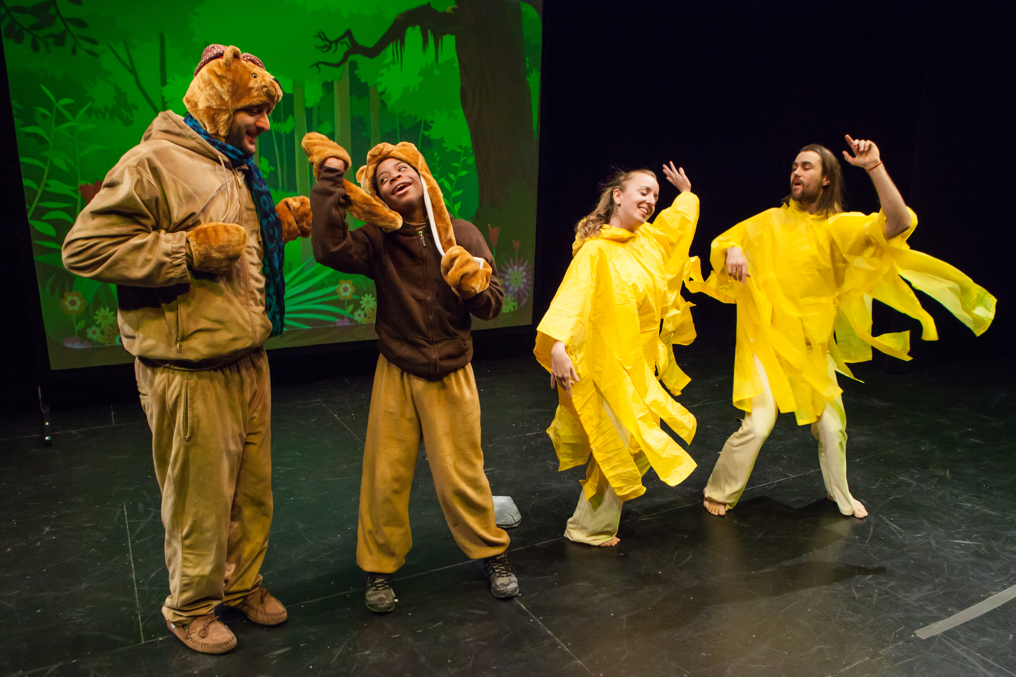 A boy and an adult in bear costumes, a womand and man dressed as sun rays. 