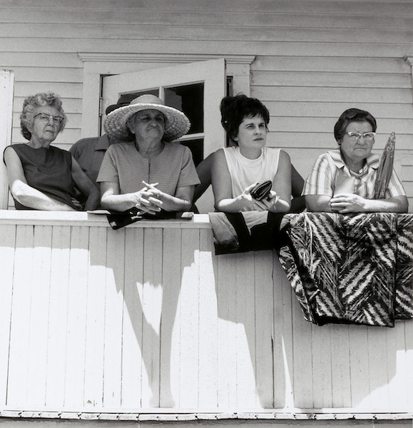 a group of four white women looking out from a balcony circa 1974