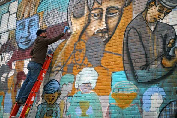 a man on a ladder adding paint to a mural