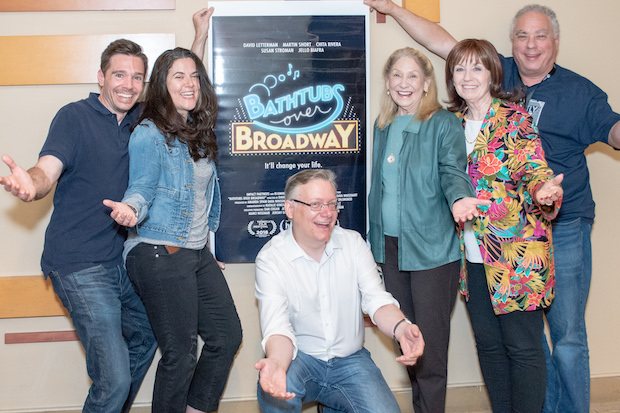 a group of people including the filmmaker posing in front of film poster for Bathtubs Over Broadway