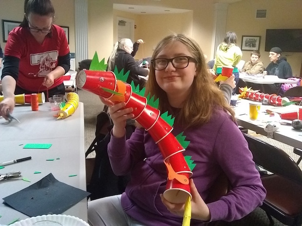 a woman showing off a dragon made of red plastic cups