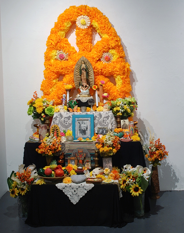 An altar made with flowers against a wall.