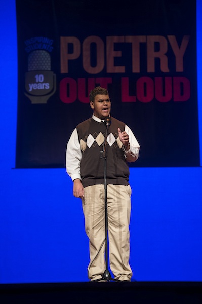 a young man recites a poem on stage
