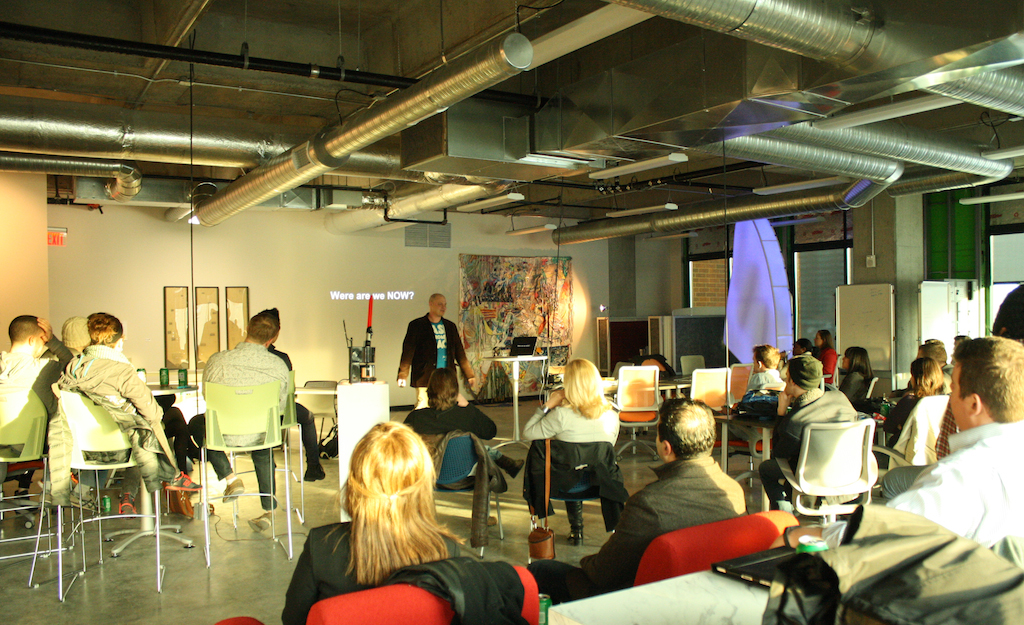 Man in front of group of people making a presentation. 