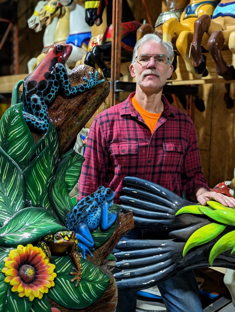 A man surrounded by carousel and carvings.
