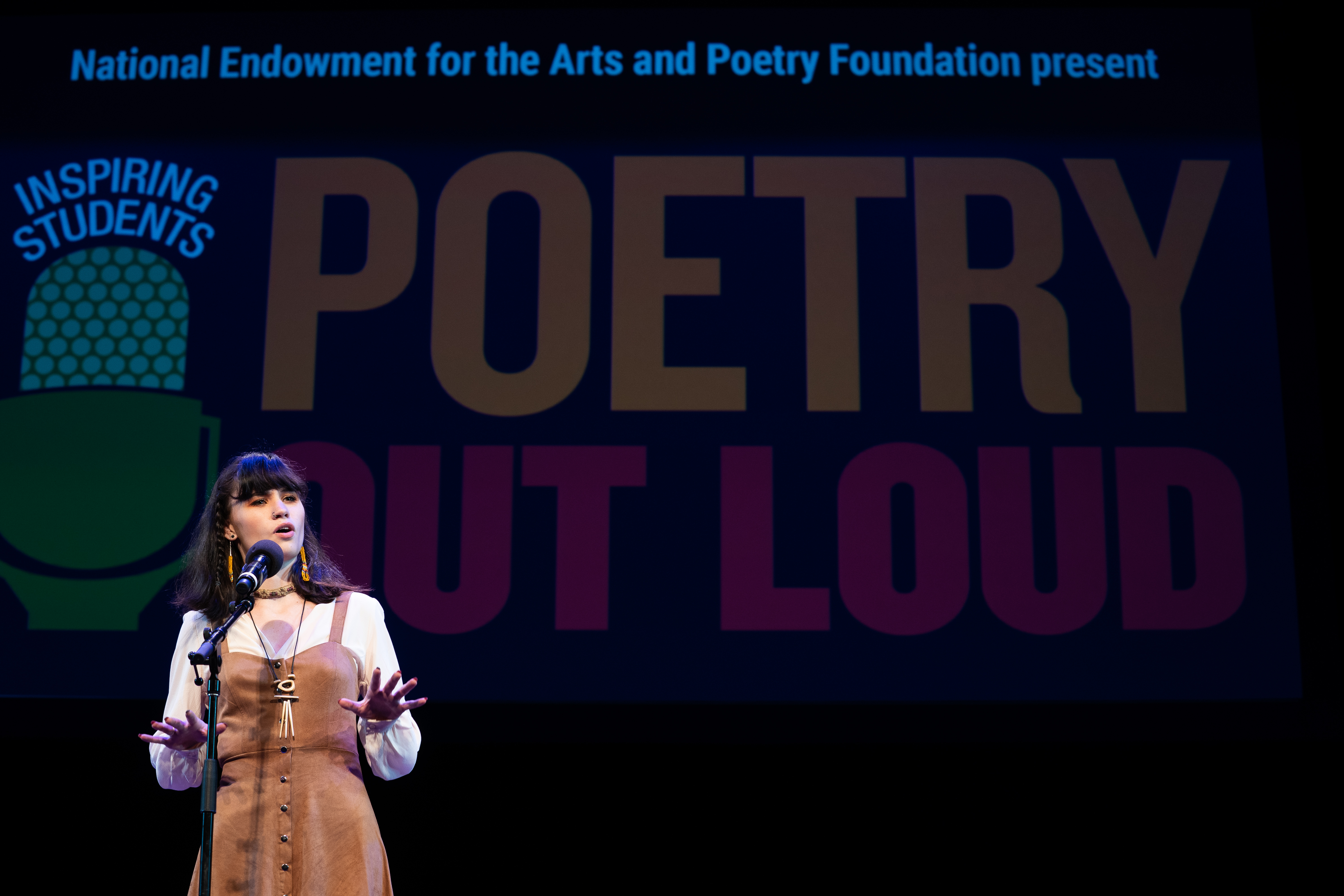 Teenage girl on stage reciting poetry