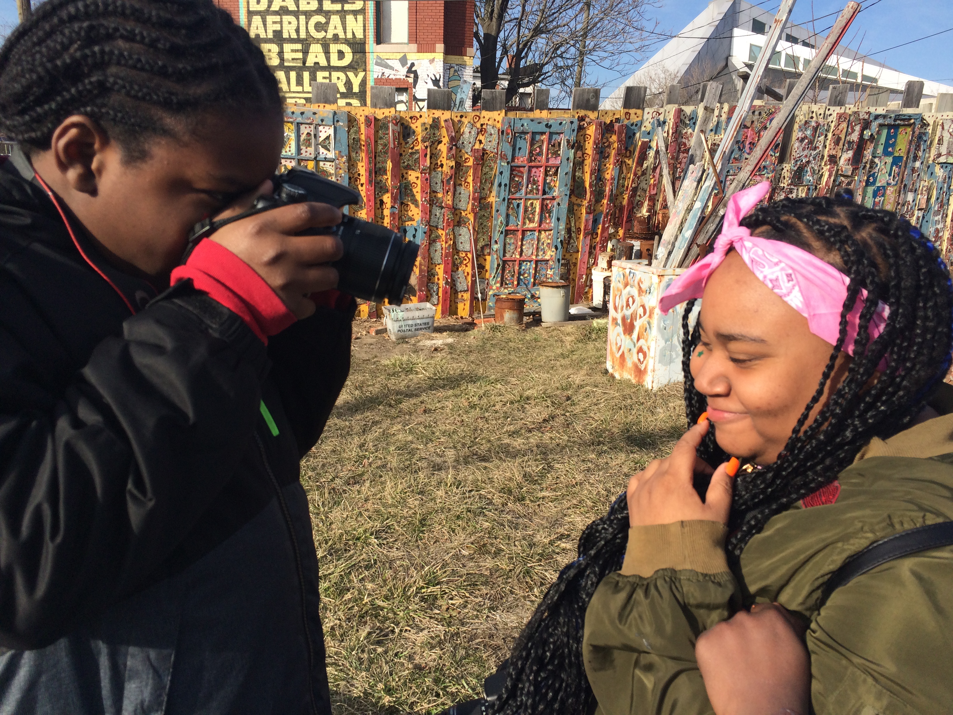 Boy photographing a girl in a yard. 