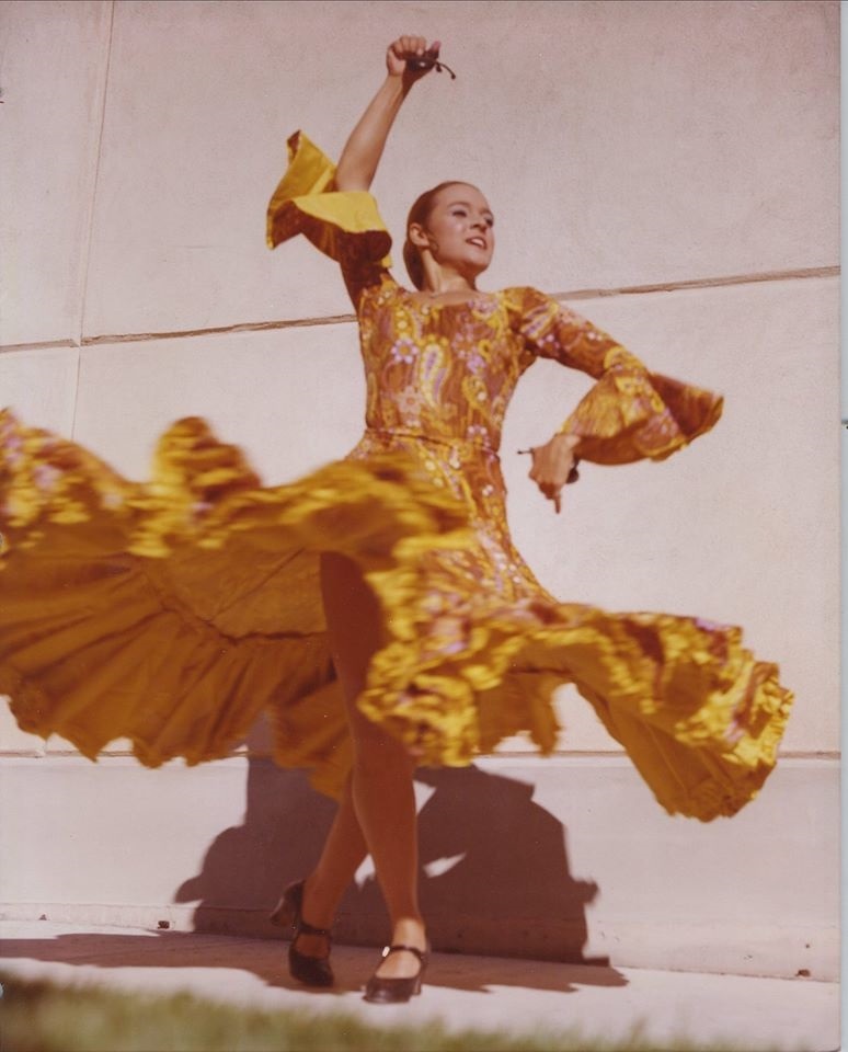 A woman dressed in a flamenco dancer dress strikes a pose.