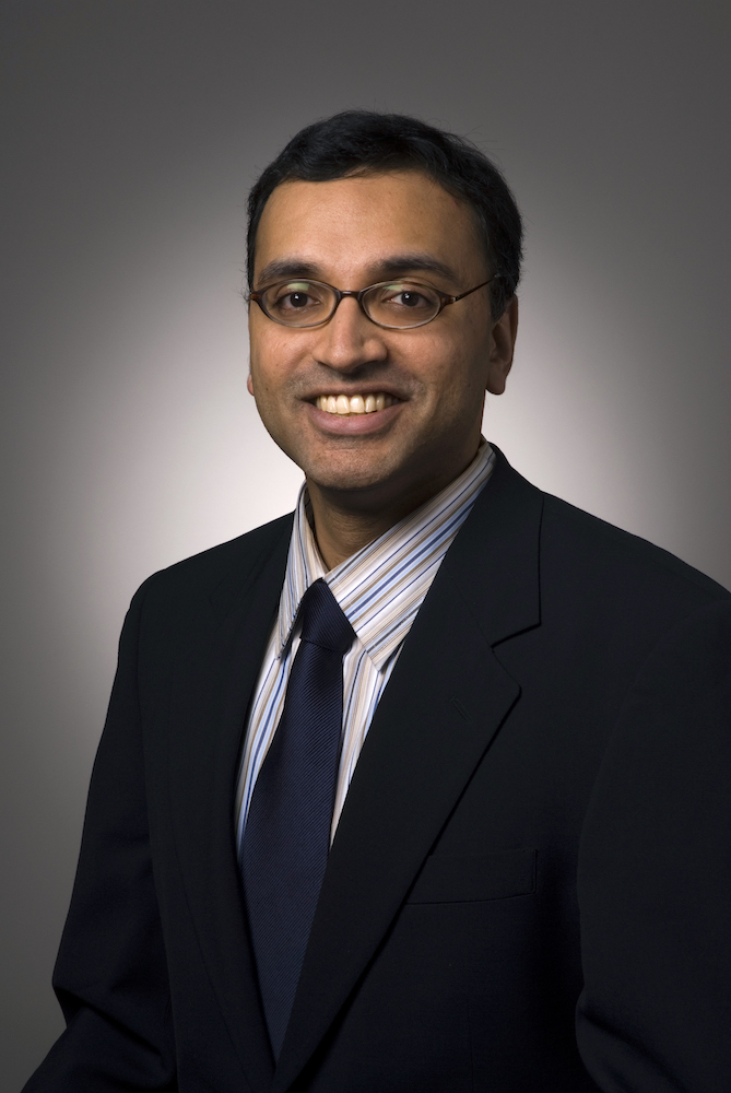 Sunil Iyengar, who is a South Asian man. He is smiling and wearing a dark suit and tie.