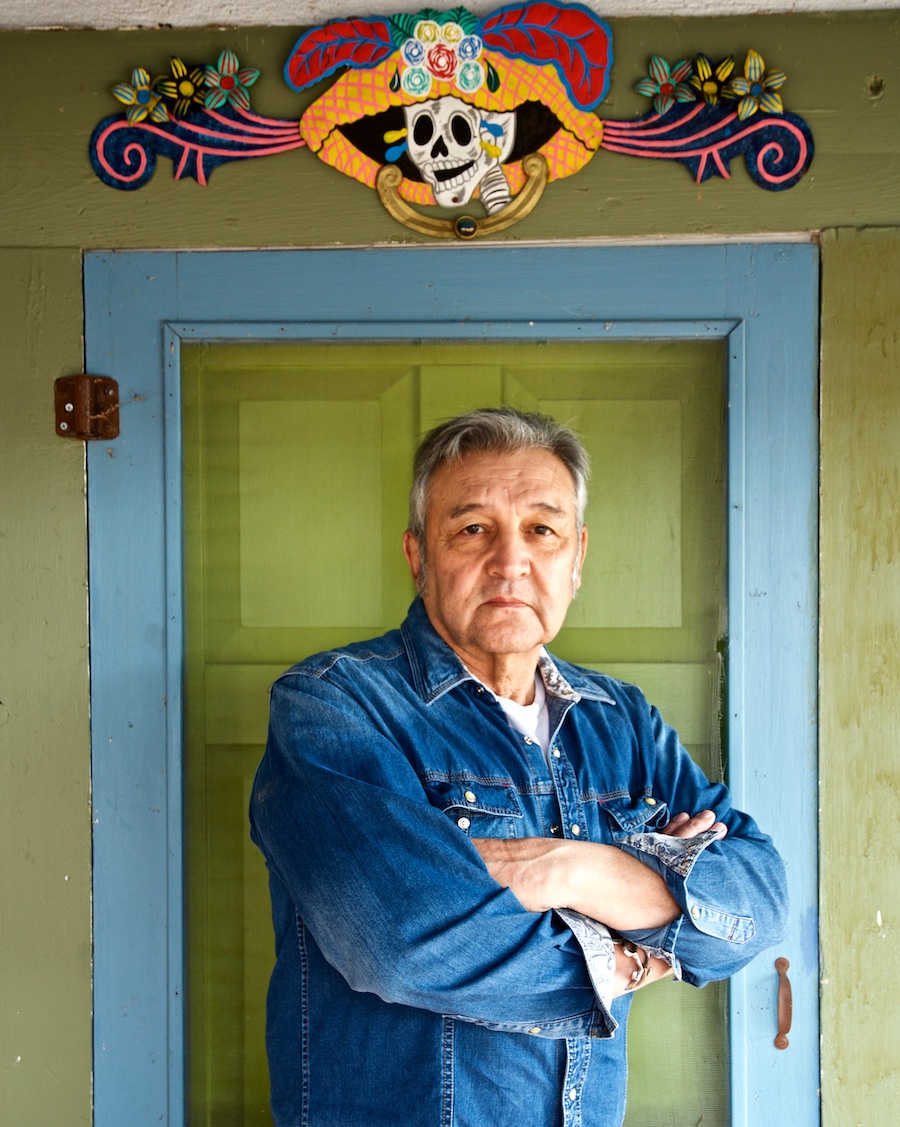 A man standing in front of a door with a colorful design over the door.
