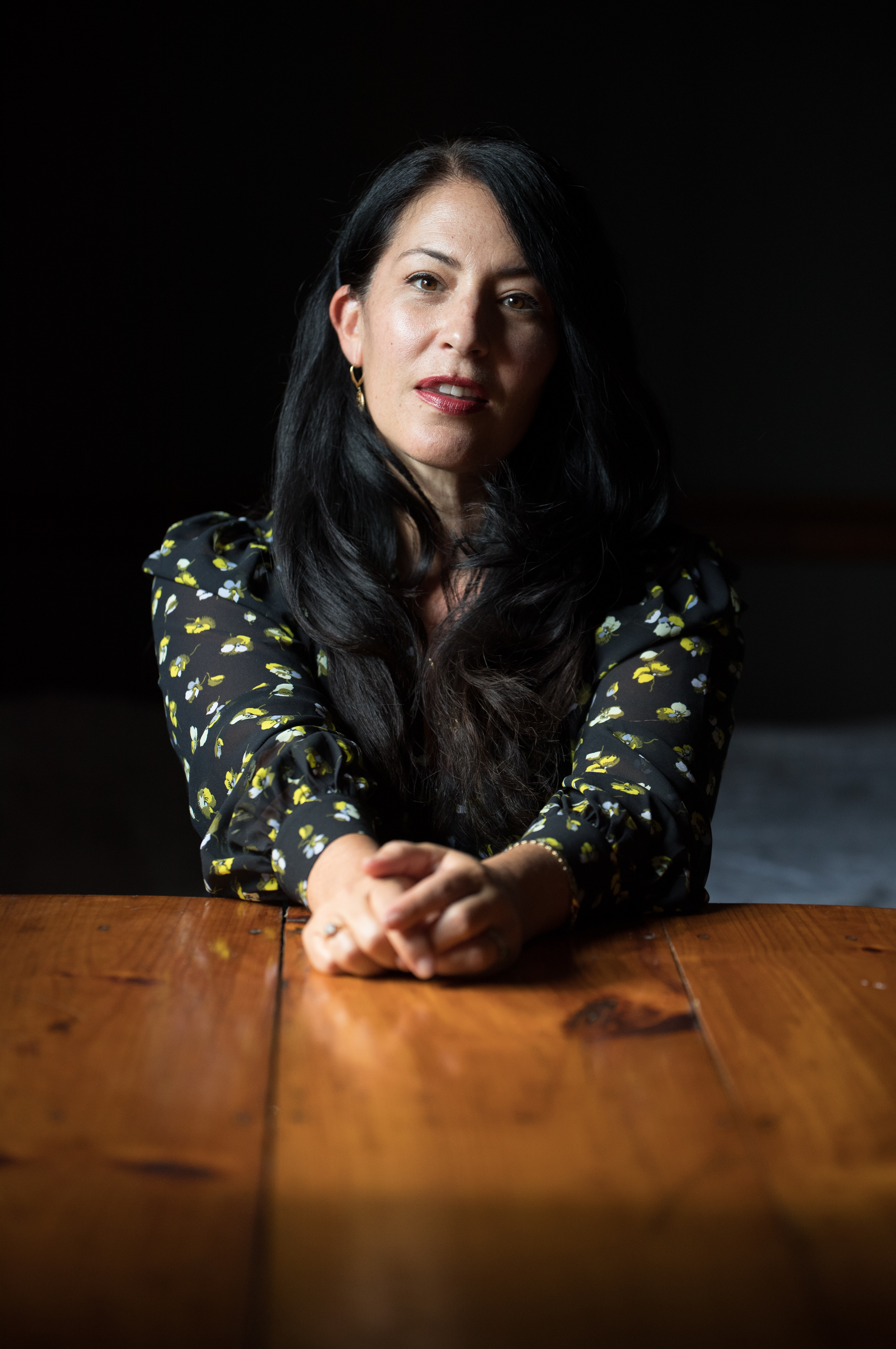 A woman poses sitting next to a table