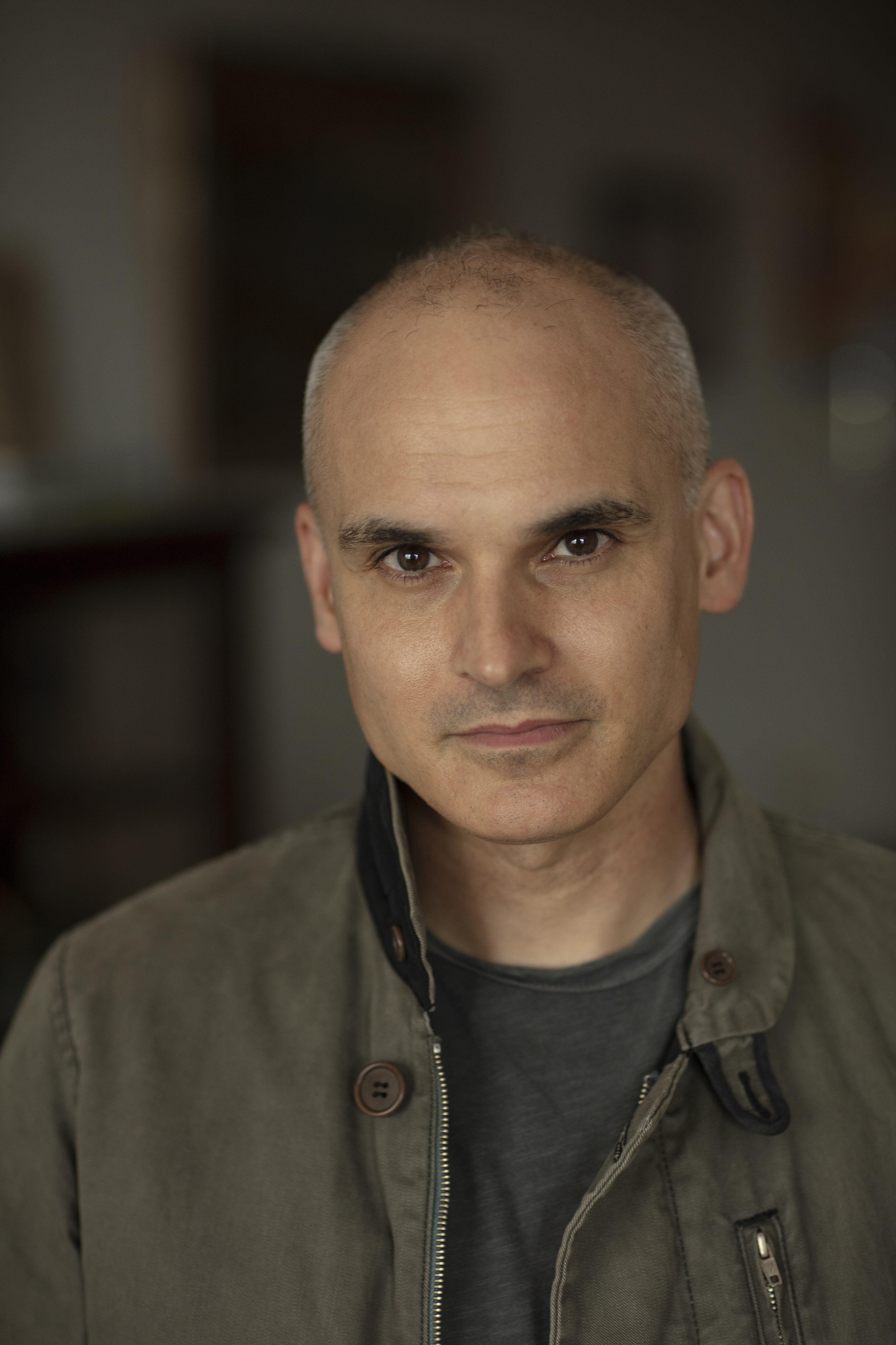 A man in a dark green shirt poses.