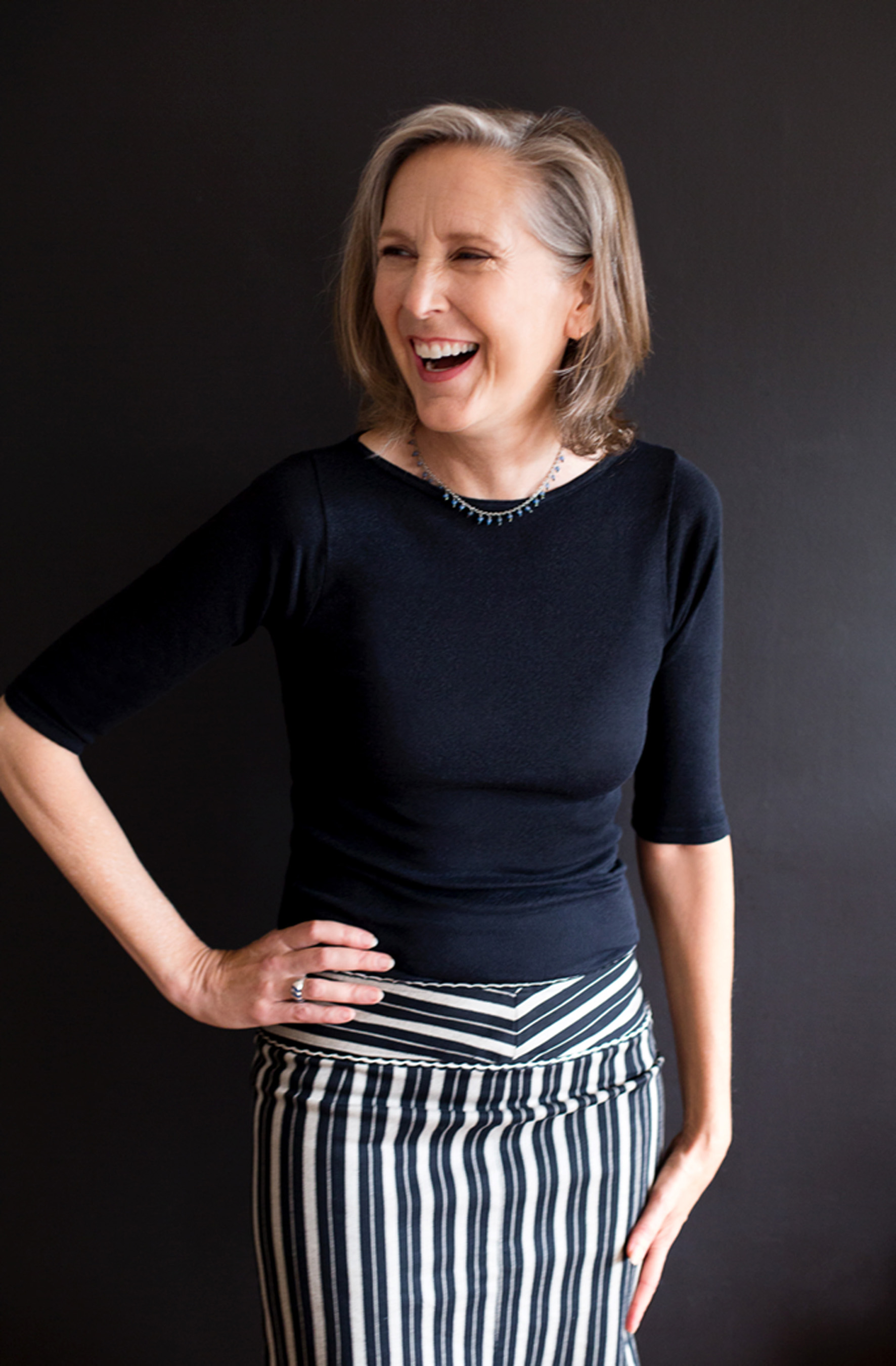 A white woman with black shirt poses in front of dark background