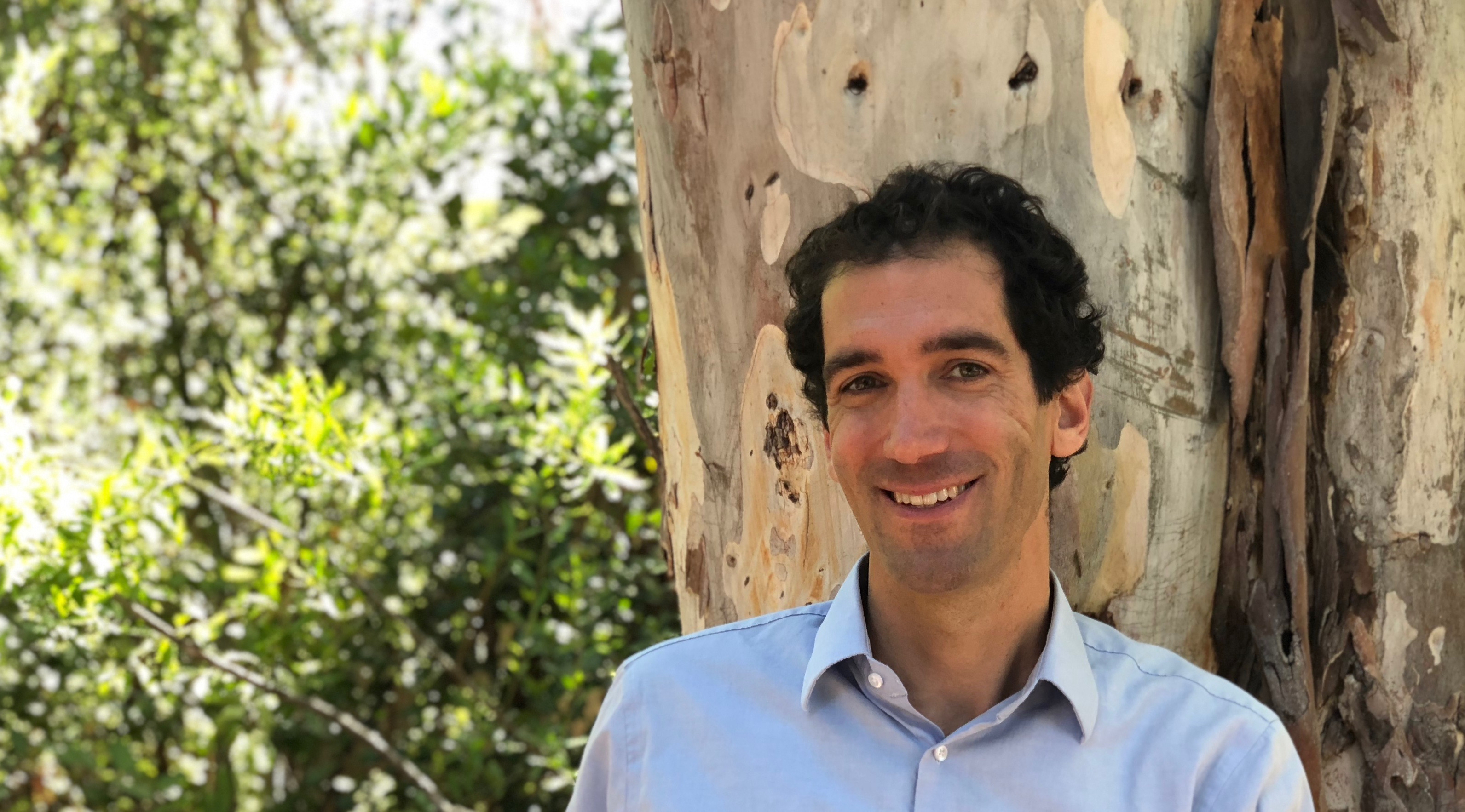 A man with light blue shirt poses.