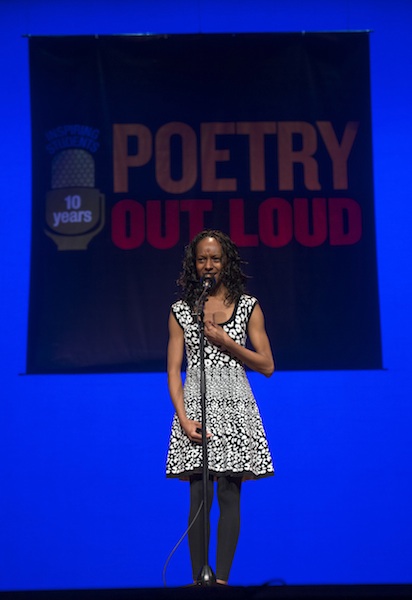 a young black woman recites a poem on stage
