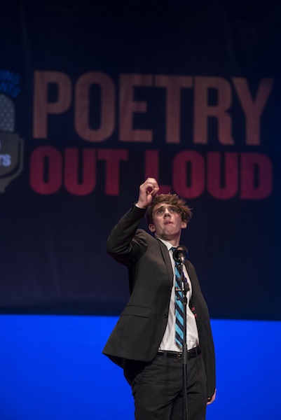 a young man enthusiastically recites a poem on stage