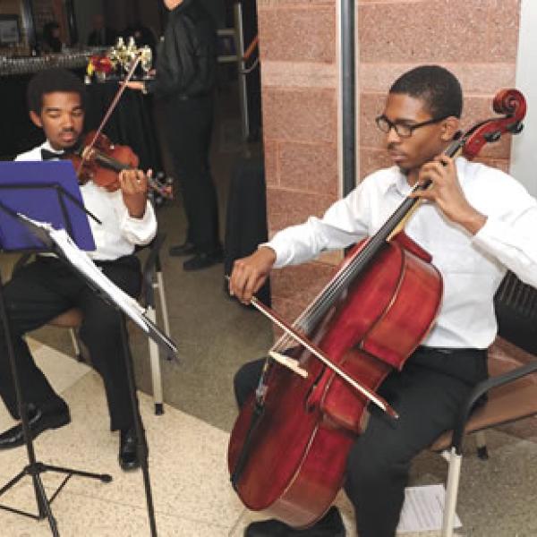 Two young men performing, one playing the violin, the other the cello