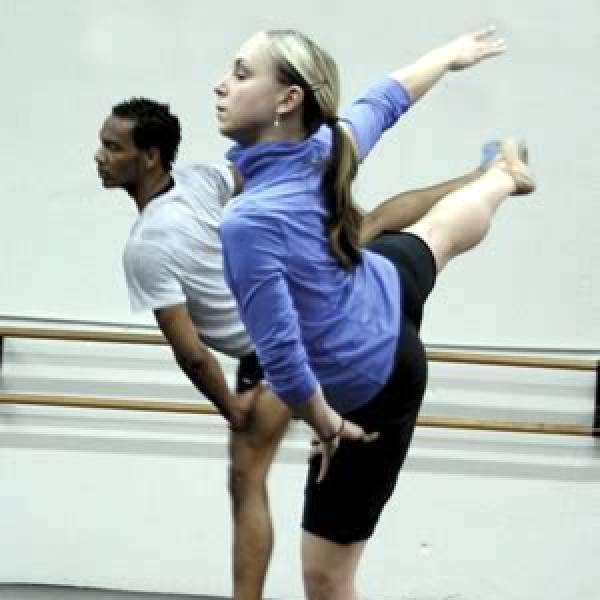 Two dancers in the studio with right right arms and legs extended out to side