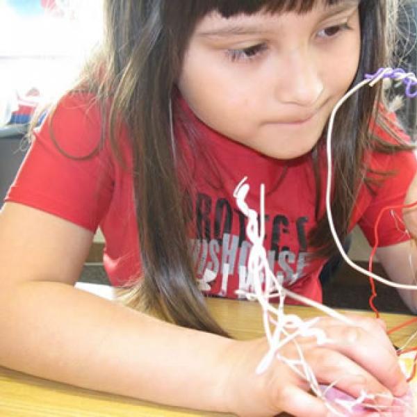 A second-grader at Quatama Elementary in Hillsboro, Oregon, lights the sculpture she created when a visual arts residency was integrated with the study of electrical circuits. Photo by Janis Hill