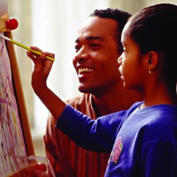 Young girl working on a painting under the guidance of her teacher