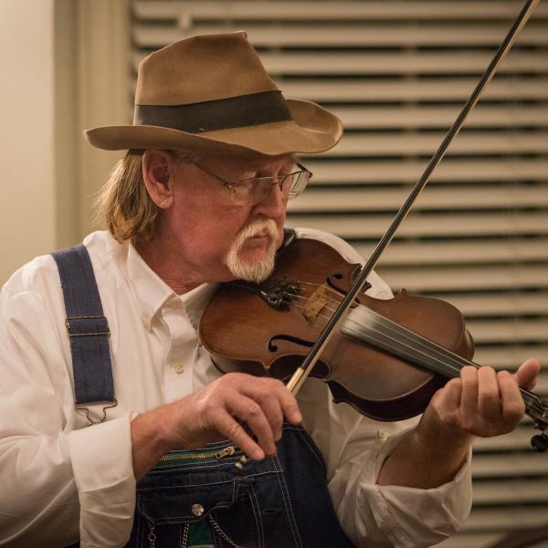 Man in hat playing a fiddle. 