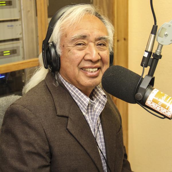 Man with headphones on in front of a radio mic.