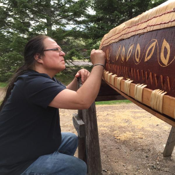 Man carving a canoe. 