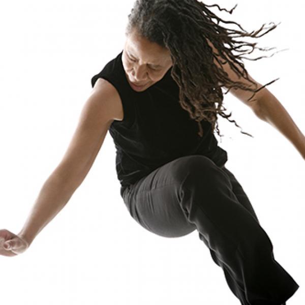 An African-American woman searing a sleeveless black shirt dancing with her eyes closed. 