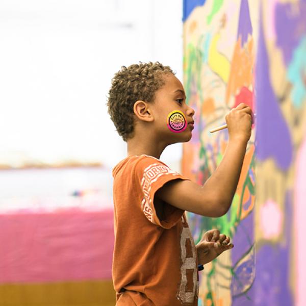 A little boy painting a mural