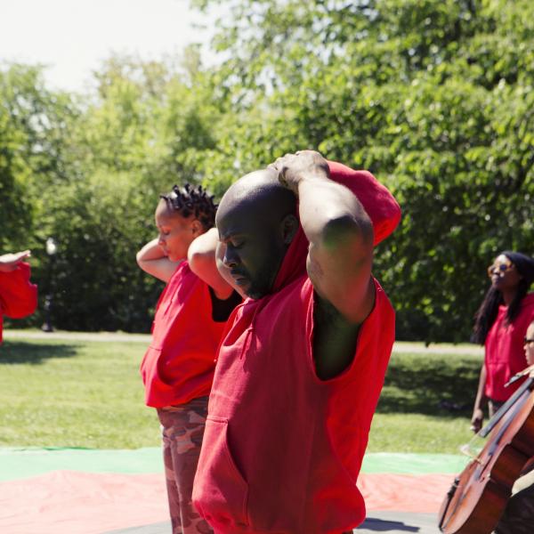 Group of people in red outfits, some with musical instruments, in Central Park. 