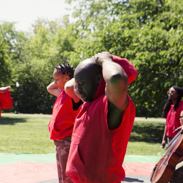 Group of people in red outfits, some with musical instruments, in Central Park.