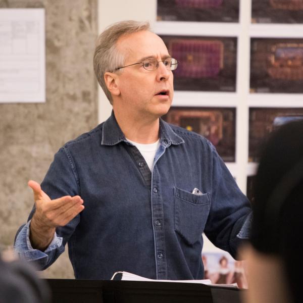 Man with glasses conducting an orchestra.