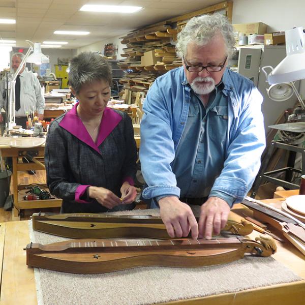 Man and woman examine a dulcimer