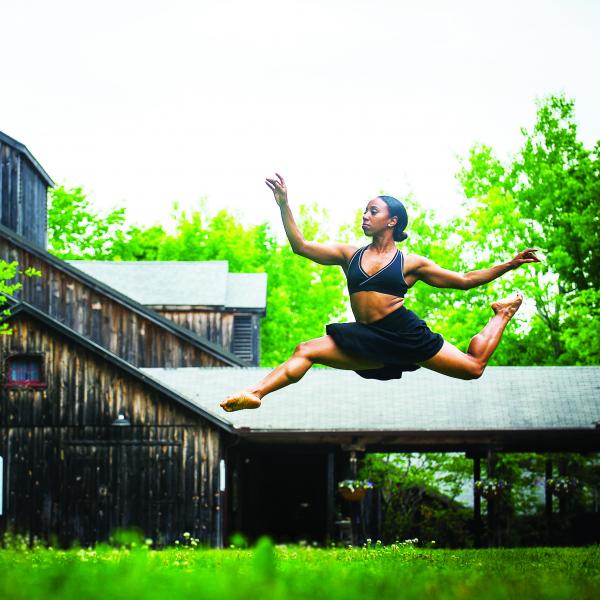 African-American dancer leaping in air before performing center.