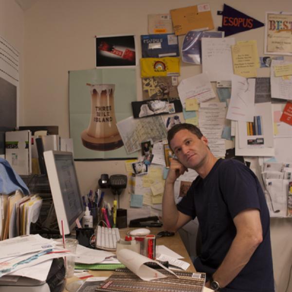 Man sitting at desk in messy office.