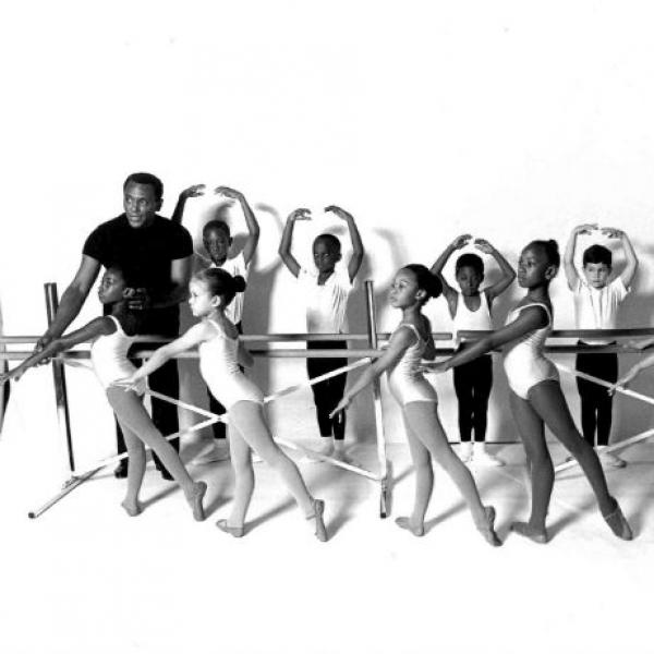Man instructing young ballerinas at ballet barre