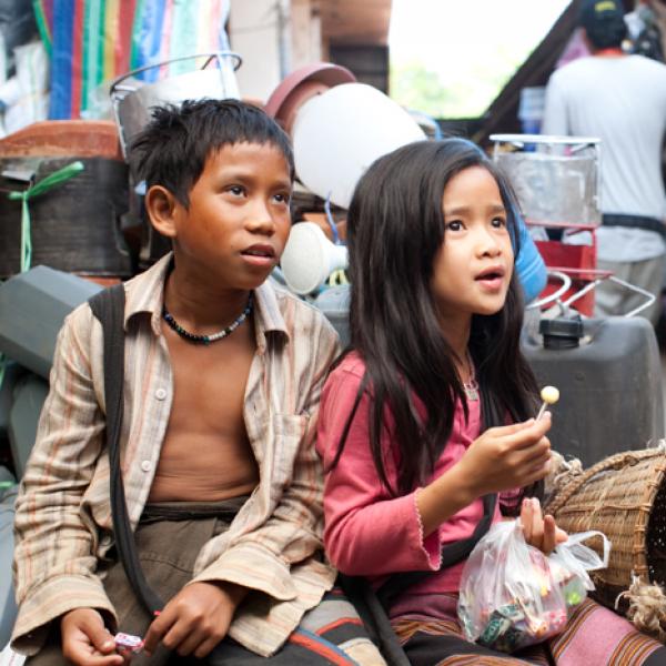 Director wearing hat with two Laotian children. 