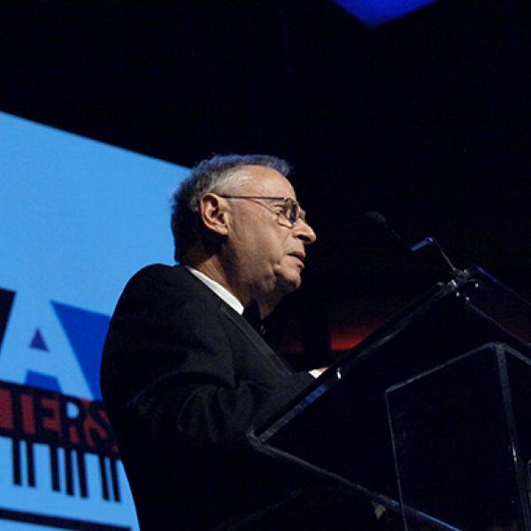 Man on stage in front of podium. 